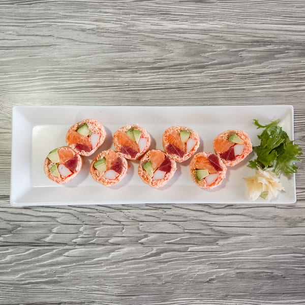 Eight pieces of sushi with salmon, tuna, avocado, and crab on a white rectangular plate.
