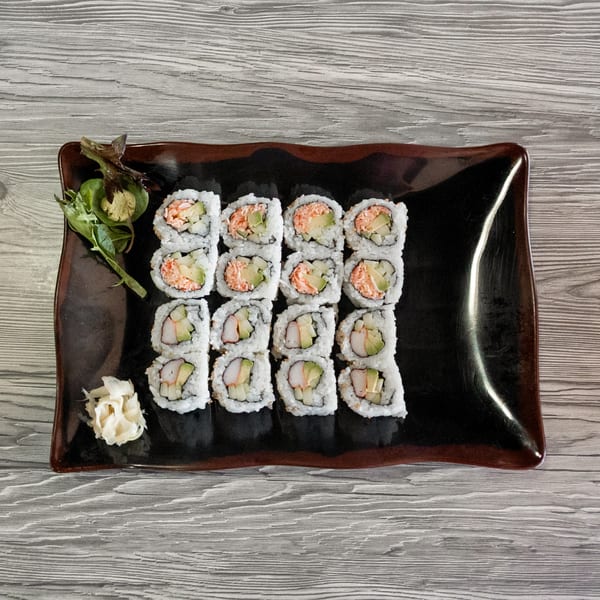 California rolls with avocado, crab, and cucumber, served with ginger and wasabi on a dark plate.